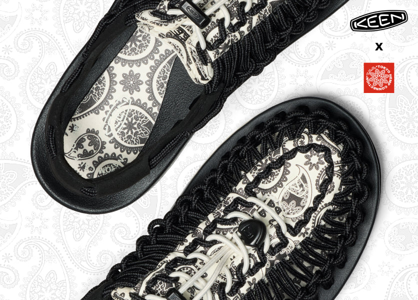 A pair of patterned, black and white UNEEK sandals.