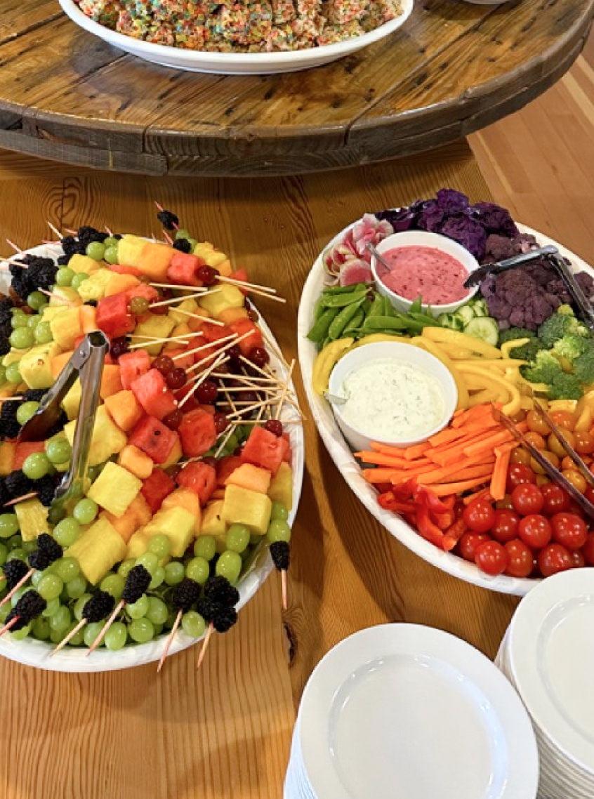 A table with a large fruit platter and a large vegetable platter.