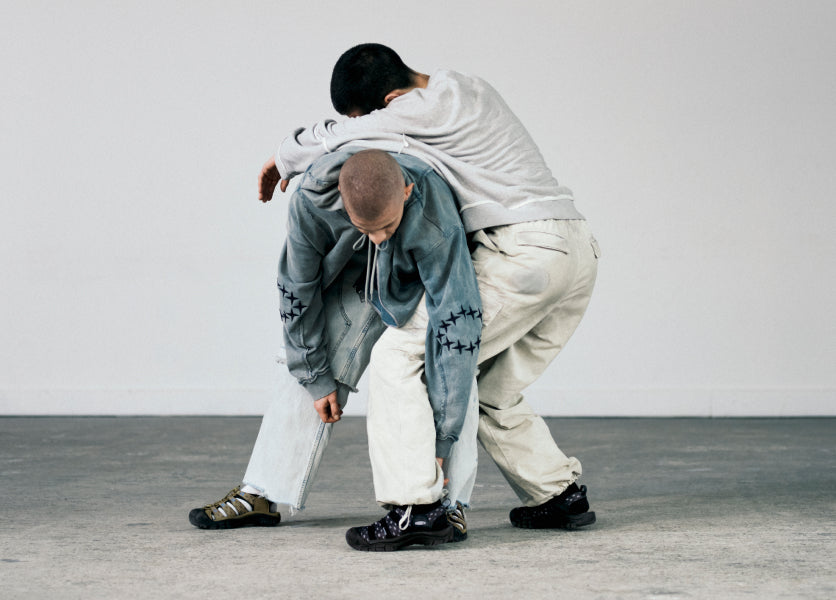 Two men wearing black and olive KEEN sandals.