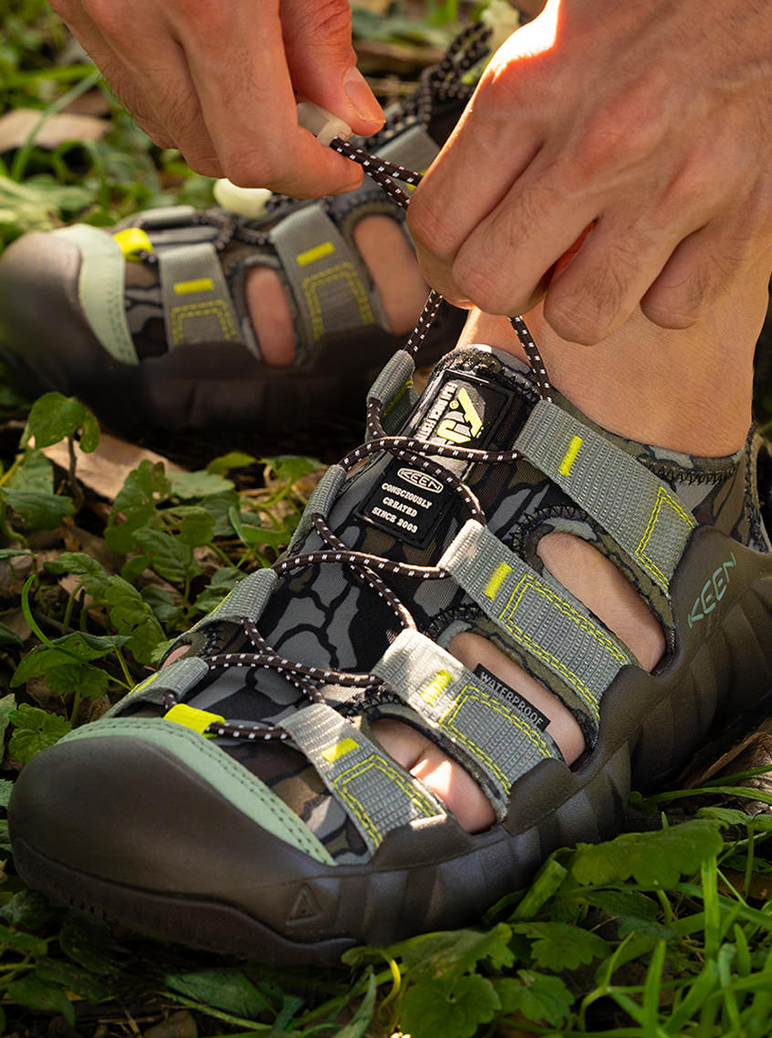 Close up shot of man wearing Keen and Fuji Rock collaboration Newport sandals and tightening the bungee laces. 