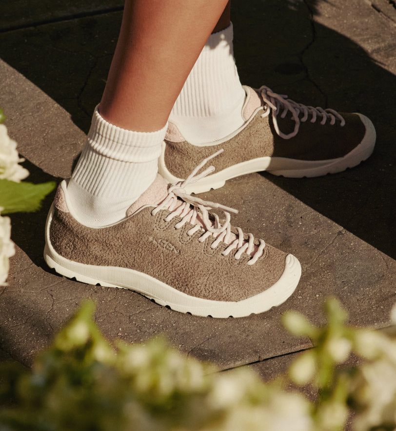 Knee-down shot of woman wearing white crew socks with Jasper Lite KM sneakers while walking on city street. 