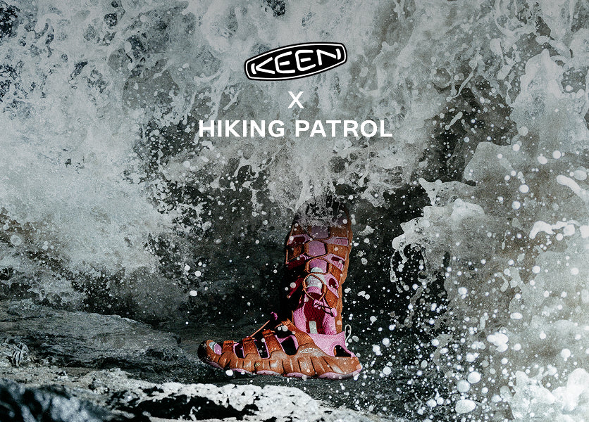 A pair of pink and orange sandals resting on a rock partially submerged in clear water, surrounded by rippling waves.