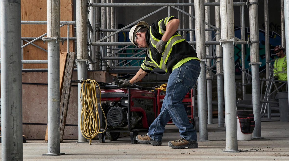 Man working with Cables on constructions site wearing high visibility sweatshirt and and work boots