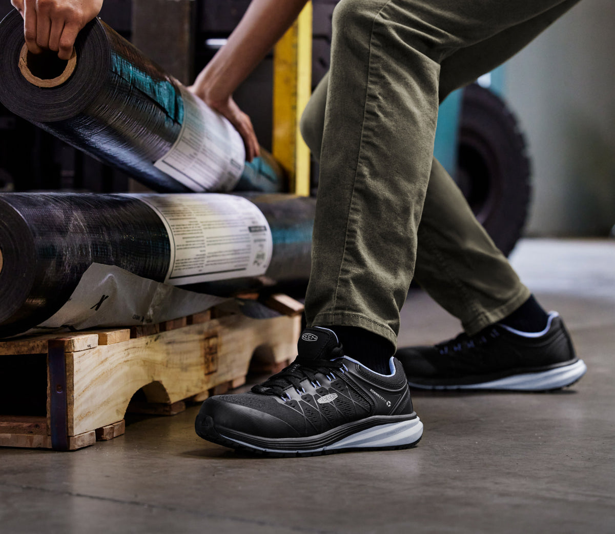 Knee down view of man wearing vista energy and stacking material on a wood palette