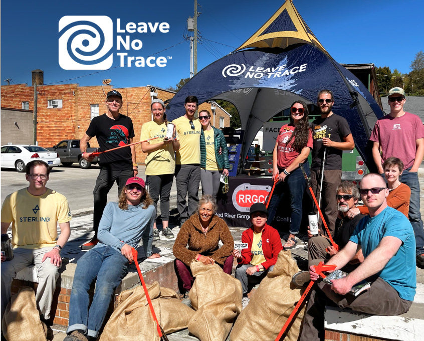 Many people sitting and standing in front of a Leave No Trace tent.