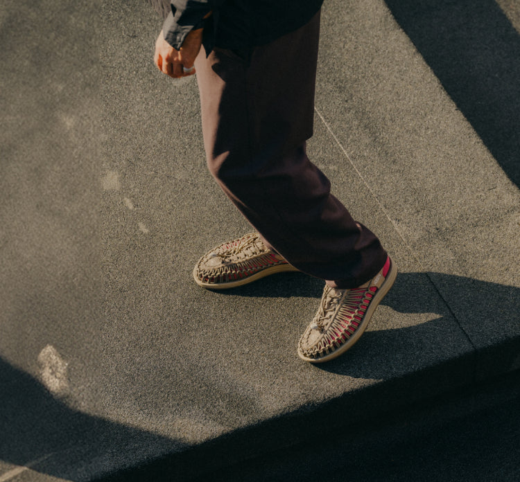 Person wearing KEEN UNEEK sandals on sunny cement steps