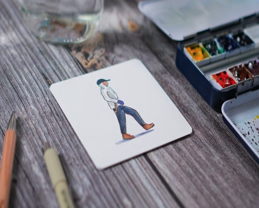 A simple painting of a person walking, on a small, white, square canvas, sitting on a picnic table.